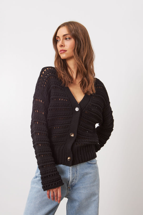 Style Brynne is a cardigan, crafted from a soft cotton yarn, boasts a practical design and features an open work mesh. It can be worn on its own or layered on top of a delicate blouse for a versatile look.

